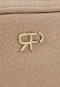 Borsa in ecopelle color pesca con superficie testurizzata, ferramenta dorata e design del logo stampato in rilievo al centro.