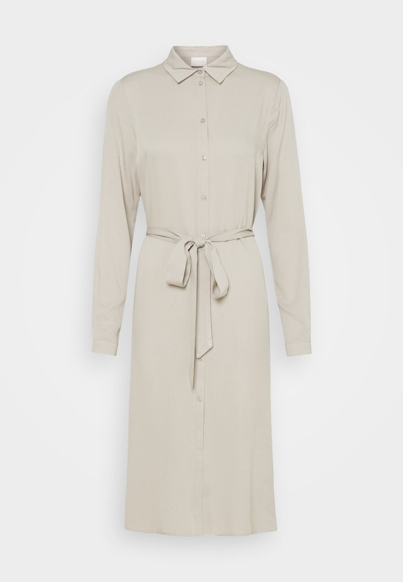 Robe-chemise longue à manches longues beige clair avec col, boutons devant et ceinture assortie en tissu à la taille, présentée sur fond blanc uni.