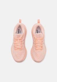 Light pink athletic shoes with a breathable mesh upper, textured accents, flat laces, and a pull tab on the heel for easy wear.