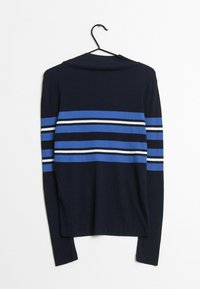 Maglione a coste di colore blu navy con strisce orizzontali blu, bianche e nere. Presenta un collo alto e maniche lunghe, appeso a un gancio.