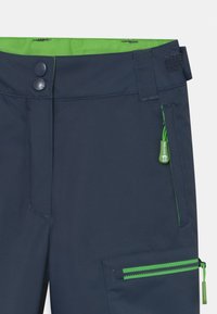 Marineblaue Hose mit grünem Innenbund, ausgestattet mit zwei Knöpfen, einer Seitentasche mit grünem Reißverschluss und sichtbaren Steppnähten.