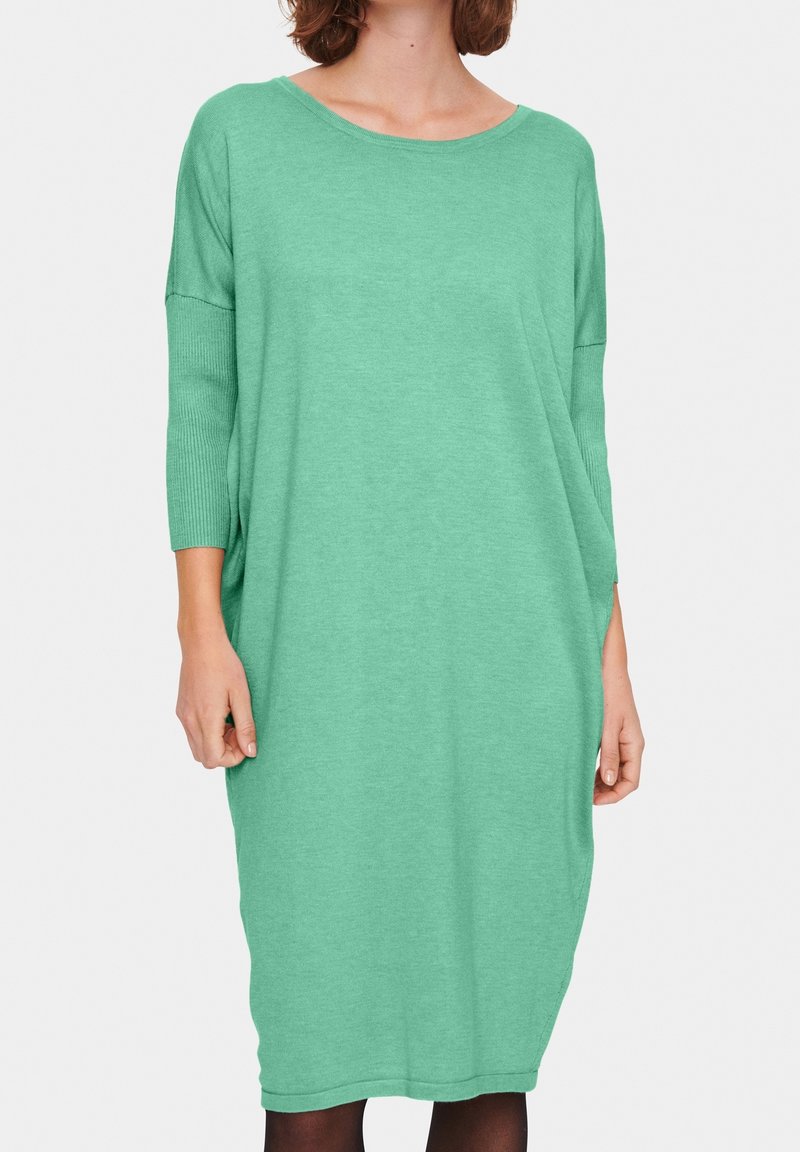 Grön, knälång klänning gjord av mjukt, texturerat tyg med lös passform, bred halsringning och trekvartslånga ärmar. Minimal design.