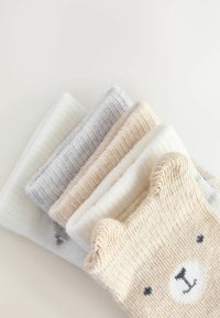 Set von vier Paar gestrickten Socken in Creme, Grau, Beige und Weiß. Ein Paar zeigt ein Bärenkopfmuster mit strukturierten Ohrdetails.