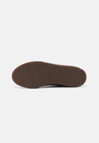 Brown rubber shoe sole with horizontal and vertical grooves for traction. Flat with round edges, no visible logos or additional details.