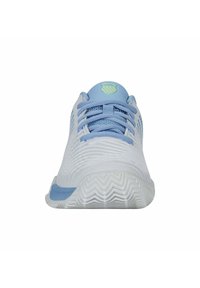 Valkoinen urheilujalkine, jossa on teksturoitu yläosa, siniset nauhat ja sininen yksityiskohta kantapäässä; sisältää vihreän logon kielessä ja sahalaitaista pohjakuviointia.