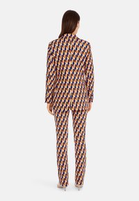 Gemusterter Blazer und Hose in geometrischem Design in Orange, Navy und Beige. Glattes Material, taillierte Passform und scharfe Revers mit schlanker Silhouette.