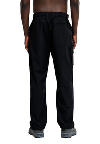 Svarta cargobyxor med elastisk midja, sidofickor och en avslappnad passform. Materialet verkar lätt och hållbart.