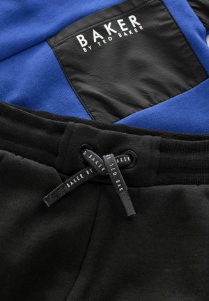 Blauwe sweater met een zwart paneel met het logo "BAKER BY TED BAKER". Zwarte joggingsbroek met een trekkoord in de taille en een gladde textuur.