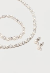 Σετ ασημένιο κολιέ, βραχιόλι και σκουλαρίκια με εναλλασσόμενους στρογγυλούς μαργαριτάρια και καθαρά πολύτιμα λίθια σε λευκό φόντο.