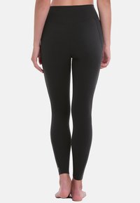 Zwarte leggings gemaakt van rekbare stof, met een hoge tailleband en een naadloos ontwerp met een gladde textuur. Geen zichtbare patronen of hardware.