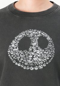 Felpa nera con un design circolare bianco composto da numerosi volti di teschi piccoli che formano la sagoma di un teschio più grande sulla zona del petto.
