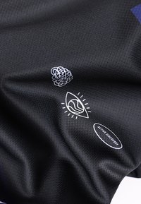 Μαύρο ύφασμα με λευκά γραφικά σχέδια που περιλαμβάνουν μια μπερδεμένη γραμμή, ένα μάτι με κυματιστό σχέδιο, και το κείμενο "ACTIVE DISCOVERY" μέσα σε οβάλ σχήμα.