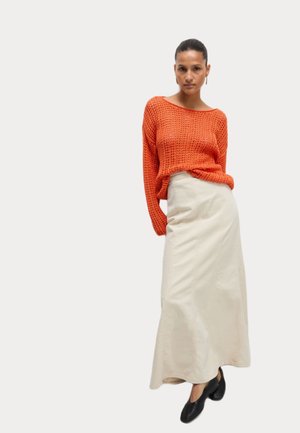 Oranger Strickpullover, beiger langer Rock mit Nähten, schwarze geschlossene Pumps. Der Stoff ist strukturiert, mit lässigem Schnitt und Off-Shoulder-Design.