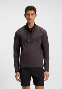 Mörklila idrottströja med halvmage, med ett texturerat geometriskt mönster på den övre framsidan och sidofickor.