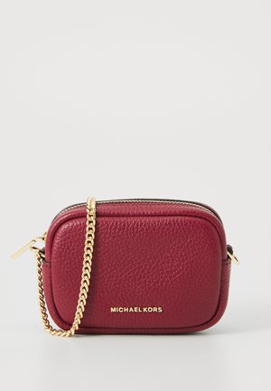 Sac bandoulière en cuir rougeâtre avec une chaîne en doré, fermeture éclair et logo en relief. Surface texturée et design arrondi.