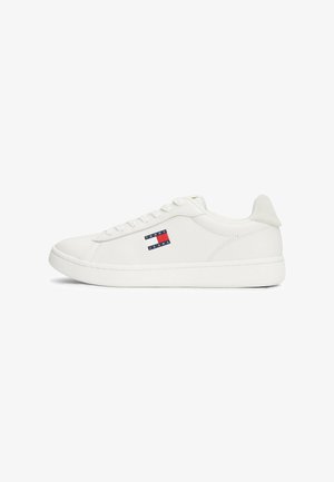 Zapatilla blanca de cuero con cordones planos, punta redonda y parte trasera texturizada. Presenta un logo azul y rojo en el lado exterior. Suela de goma.
