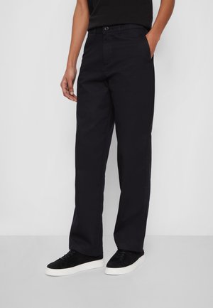 Mørk navy bomulds chinos med lige ben og sidelommer, samt en lukning med knap foran, samlet med sorte sneakers.