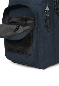 Mörkblå ryggsäck med en strukturerad tyg, en ficka med dragkedja fram och en nätpanel på sidan med ett hållbart dragkedjestängning.