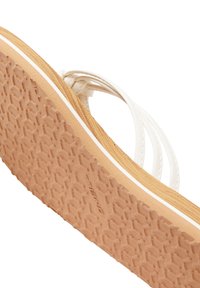 Hvide flip-flops med en tekstureret gummisål og flettede stropper. Har en lysebrun bund med en tynd hvid accentlinje.