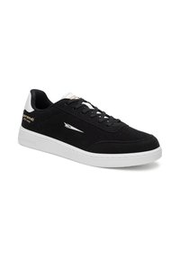 Pantofii sport negri cu vârful jos au talpa și călcâiul alb, șireturi negre și un logo alb pe lateral și pe călcâi.