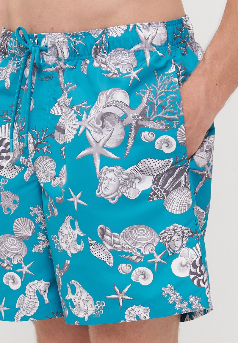 Turkise badetights med et mønster af grå havdyr, skaller og koraller, med elastisk talje og snørre.