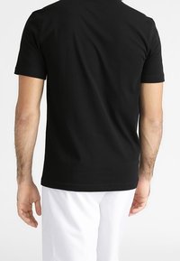 Svart bomullströja, korta ärmar, klassisk rund halsringning, figursydd passform, slät textur, inga synliga motiv eller mönster.