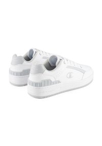 White athletic sneakers with a smooth leather upper, gray accents, padded collar, and a textured rubber sole featuring grooves.