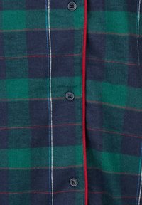 Chemise à carreaux avec motifs à carreaux vert foncé et bleu marine, agrémentée d'accents rouges et de boutons. Le tissu a une texture douce.