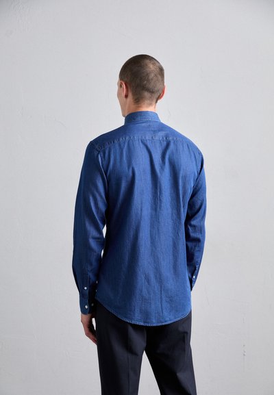 Cămașă din denim în nuanță bleu închis, cu mâneci lungi, guler ascuțit și tiv curbat. Prezintă un material texturat și manșete cu nasturi.