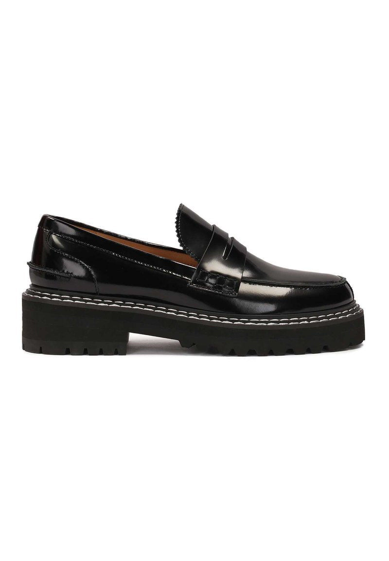 Black patent leather loafers with a chunky black rubber sole, accentuated by white stitching and a decorative front strap.