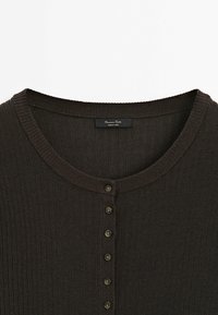 Donkere bruine geribbelde gebreide cardigan met een ronde halslijn en een zevenknopenlijst. Subtiele textuur met een zachte afwerking.