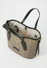 Tote bag featuring a woven beige and black striped exterior, black leather accents, and an interior with vertical striped lining and a zipper pocket.