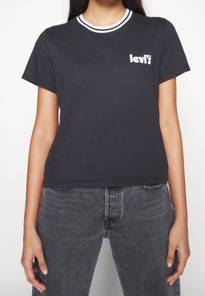 Woman wearing black Levi's t-shirt with white logo on chest and striped collar, paired with faded black jeans.