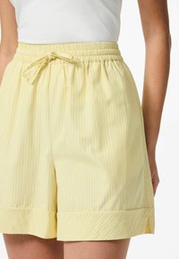 Dzelteni, svītraini šorti ar elastīgu jostasvīru un saišu detaļu. Piedāvā platumu apakšmalā un mīkstu audumu, ideāli piemēroti ikdienas valkāšanai.