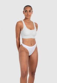 Witte naadloze bralette met een ronde halslijn en brede bandjes, gecombineerd met een bijpassende witte string. Glad stof, minimalistisch ontwerp.