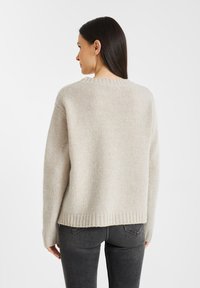 Lichtbeige gebreide trui met een ronde hals, geribde mouwen en een zoom, met een iets oversized pasvorm en een textuurstof.