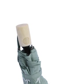 Paraguas de tela verde con un mango de madera texturizada, que cuenta con múltiples paneles, acentos cosidos y una correa en bucle para llevar.