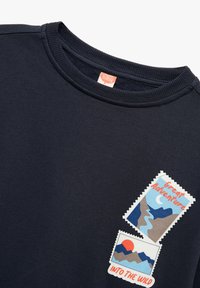 Sudadera marina con cuello redondo acanalado, con dos impresiones en estilo parche que representan paisajes y el texto "Gran Aventura" y "Aventura en la Naturaleza."