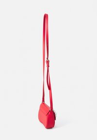 Rode neplederen tas met een slanke silhouette, verstelbare schouderriem en zilveren hardware-accenten. Gladde textuur, eenvoudig ontwerp, geen zichtbare patronen.