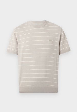 Světlé béžové krátké pletené tričko s tenkými vodorovnými bílými pruhy a malou čtvercovou nášivkou s logem na levé straně hrudníku.