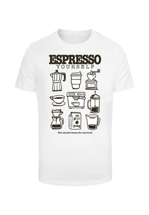Biela tričko s čiernymi ilustráciami kávovarov, šálok a kartónu s textom "ESPRESSO YOURSELF" nad ním a "Posvätné veci na prežitie" pod ním.