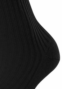 Svart ankelsocka i ribbat tyg, med en sömlös tå och en texturerad yta, samt en åtsittande passform vid vristen.