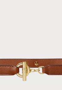 Hnedý kožený remienok s detailom zlatého kovového okrúhleho hardvéru a uzáverom na preklápací mechanizmus, s kontrastným prešívaním pozdĺž okrajov.