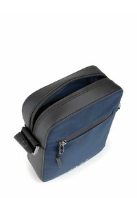 Sac en tissu bleu marine avec des accents en cuir synthétique noir, compartiments zippés et une sangle réglable. Présente des coutures visibles et un logo.