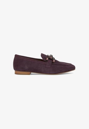 Mocassin en daim violet avec une semelle plate et des embellissements sur le dessus. Présente une forme arrondie à l'avant et un détail de couture le long du bord.