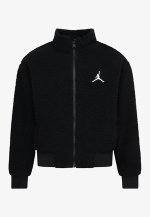 Veste en polaire noire avec col haut, fermeture éclair intégrale, poignets élastiques et ourlet côtelé. Logo brodé blanc notable sur la poitrine.