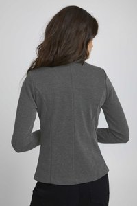 Camiseta gris de manga larga con un diseño ajustado, tela texturizada y un detalle de costura que recorre verticalmente la parte posterior. El dobladillo llega a la cintura.