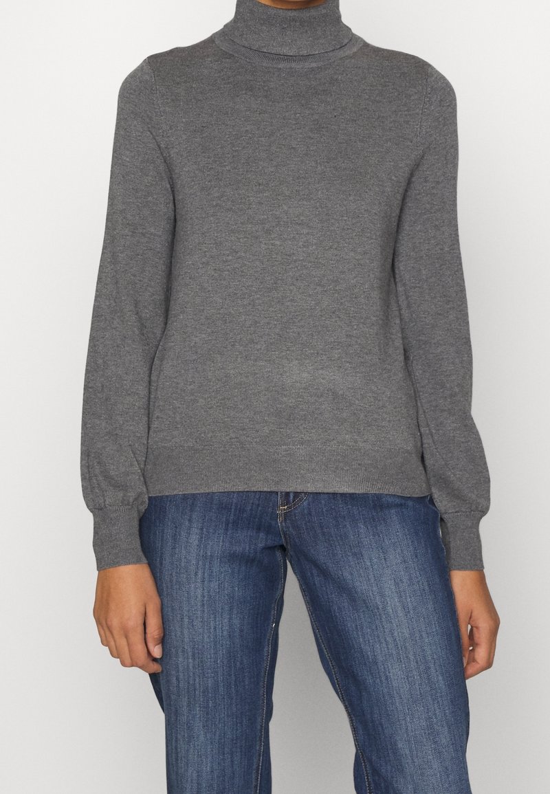 Pull à col roulé gris à manches longues, texture en maille douce, poignets et ourlet côtelés, accompagné de jean en denim. Design simple et classique.