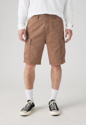 Brune cargo shorts med store sidelommer, lavet af slidstærkt bomuldsstof. Trimmet kant og en afslappet pasform, parret med sorte sneakers og hvide sokker.