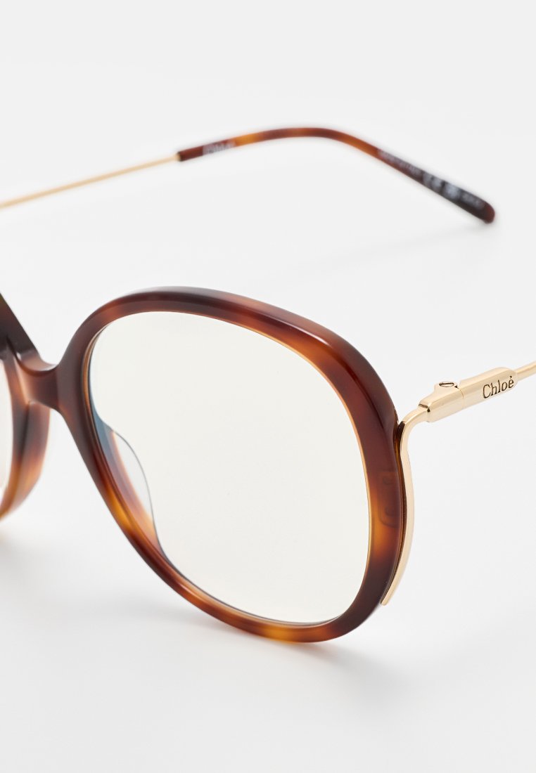 Schildpatt-Sonnenbrille mit rundem Rahmen, goldenen Metallakzenten und klaren Gläsern. Die Spezifikationen umfassen ein Design mit dicken Bügeln.